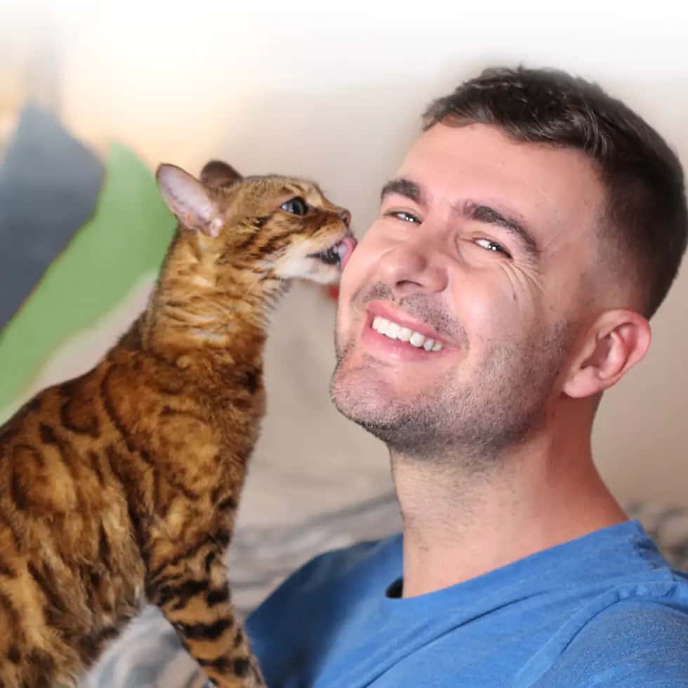 Cat licks man's face as he smiles